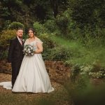 Bride and groom smiling in garden setting.