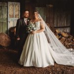 Bride and groom pose in rustic setting.