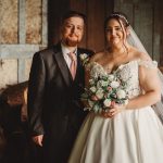 Bride and groom indoors with floral bouquet.