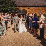 Newlyweds walk through confetti amid cheering guests.