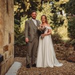 Bride and groom stand in garden.