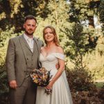 Bride and groom outdoors in wedding attire.