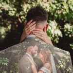 Bride and groom embrace in nature setting.