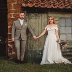 Bride and groom holding hands in rustic setting.