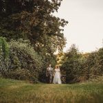 Couple walking through lush green garden path.