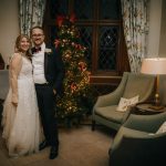 Couple by Christmas tree in elegant room.