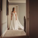 Bride in hallway wearing elegant wedding dress.