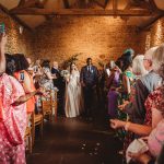 Bride and groom exit wedding ceremony with confetti.