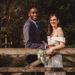 Bride and groom smiling on rustic bridge.