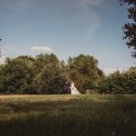 Bride and groom walking in scenic garden setting.