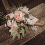 Rustic bouquet of pink flowers on wooden bench.