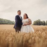 Smiling couple in wheat field on wedding day.