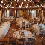 Rustic barn wedding reception with decorated tables and lights.