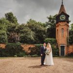 Wedding couple outside brick tower and garden.