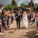 Bride and groom walk through cheering wedding guests.