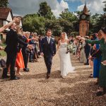 Bride and groom walking through cheering guests.