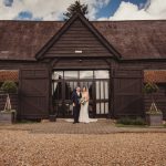 Couple standing outside rustic barn wedding venue.