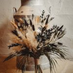 Dried flower bouquet beside vintage milk churn.