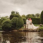 Couple in wedding attire by a scenic river.