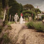 Bride and groom walking in a garden path.