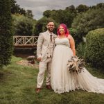 Bride and groom smiling in garden setting.