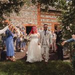 Wedding couple celebrated by guests outside venue.