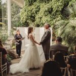 Outdoor wedding ceremony in lush garden setting.