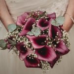 Bride holding maroon floral wedding bouquet