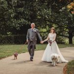 Bride and groom walking dogs in a park