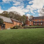 Historic brick buildings and green lawn under blue sky.