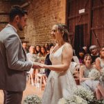 Bride and groom exchanging vows with guests watching.