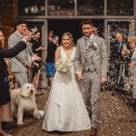 Bride and groom exiting with confetti and guests.