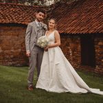 Bride and groom standing outside by brick building.