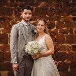 Bride and groom posing against brick wall