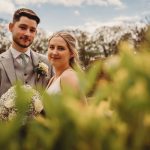 Bride and groom smiling with floral background.