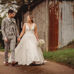 Bride and groom walking outdoors, holding hands.