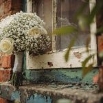 Bouquet of flowers by rustic brick wall window.