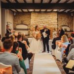 Wedding ceremony in a rustic venue with guests seated.