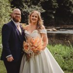 Bride and groom smiling by the river