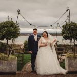 Wedding couple smiling by lakeside venue.