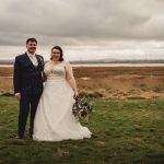 Wedding couple standing in countryside landscape.