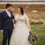 Bride and groom smiling outdoors on wedding day.