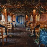 Rustic indoor wedding ceremony with wooden seating.