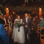 Bride walking down the aisle with father, wedding guests.