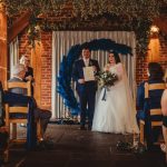 Bride and groom holding certificate at wedding ceremony.