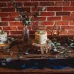 Three rustic cakes with greenery on wood table.