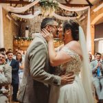 Couple kissing at wedding ceremony, guests watching