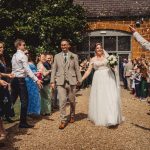 Newlyweds walking through joyful crowd at wedding celebration.