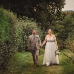 Bride and groom walking down garden path.