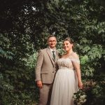 Bride and groom in lush forest setting.